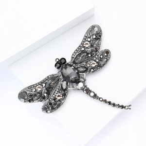 Detailed close-up of a vintage dragonfly brooch with champagne crystals and dark grey stones