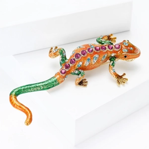 Macro shot of colorful enamel lizard brooch with sparkling rhinestones on white geometric block