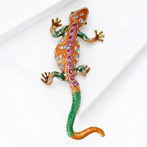 Macro detail of enamel lizard brooch with vibrant rhinestones on a white geometric background