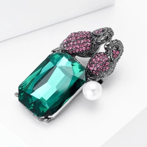 Macro detail of emerald-cut gemstone parrot brooch with pink crystals and pearl