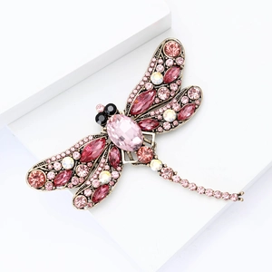 Macro detail of alloy dragonfly brooch featuring sparkling pink rhinestones and vintage gold