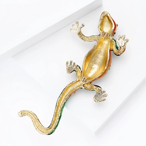 Back view of gold lizard brooch with enamel details and secure safety pin fastener