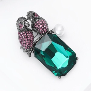 Detailed close-up of emerald-cut green crystal parrot brooch with pink rhinestones