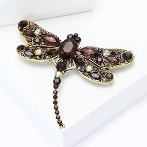 Macro shot of vintage dragonfly brooch with red crystals and antique gold finish