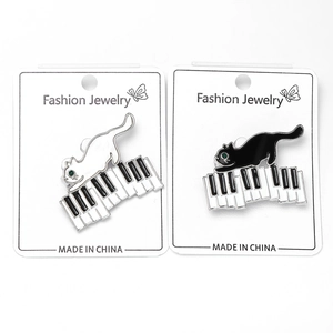 Détail de broches en émail chat sur piano avec emballage de bijoux fantaisie