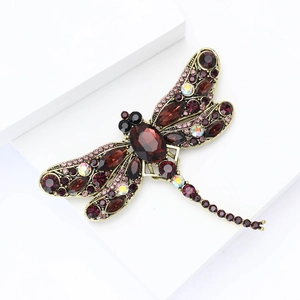 Detailed macro view of vintage gold dragonfly brooch with burgundy rhinestones and crystals