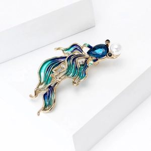 Detail of goldfish brooch featuring blue enamel fins, waterdrop stone, and a white pearl