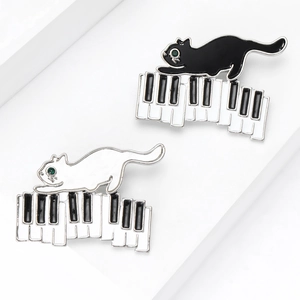 Broches en émail chat sur clavier de piano avec yeux en pierres précieuses vertes