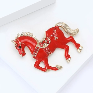 Detailed close-up of a red enamel horse brooch with sparkling rhinestones on gold base