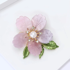 Macro detail of cherry blossom brooch with pink resin petals and pearl center