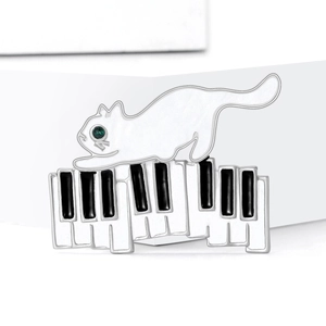 Broche chat blanc s'étirant sur des touches de piano avec yeux en strass et finition émail