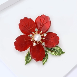 Macro detail of red enamel flower brooch with center pearl and sparkling rhinestone accents
