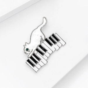 Détail de la broche chat créative avec touches de piano, émail blanc et pierre verte