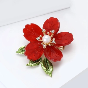 Macro shot of luxury red enamel flower brooch with center pearl and crystal details