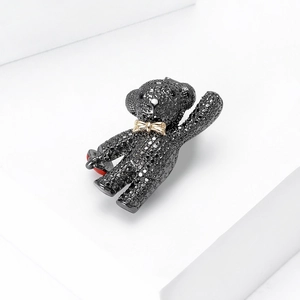 Close-up of black pave crystal teddy bear brooch with red heart and gold bowtie detail