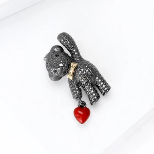 Detailed view of black rhinestone bear brooch with gold bow and a red heart charm