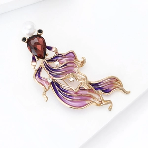 Detail of goldfish brooch with purple enamel tail and red gemstone head on white background