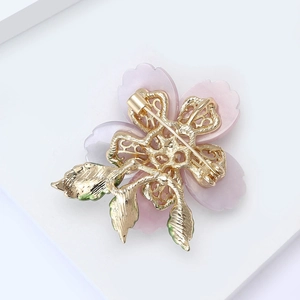 Detailed back view of pink flower brooch with golden hollow bracket and metal safety pin