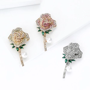 Elegante rozenbroches in drie kleuren met strassteentjes en parels op wit podium