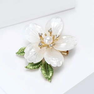 Macro shot of elegant enamel flower brooch with pearl center and sparkling crystals