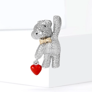 Sparkling rhinestone teddy bear brooch with red heart charm and gold bow on white cubes