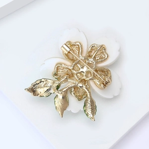 Detailed back view of enamel flower brooch with secure golden pin and safety rotating lock