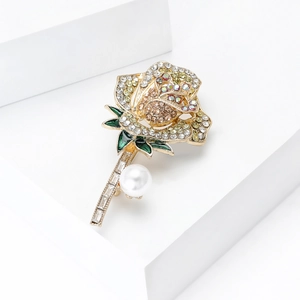 Gedetailleerde macro van rozenbroche met gele strassteunen, groen emaille en parel