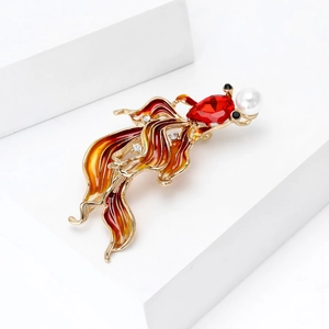Detail view of goldfish brooch featuring red crystal head and enamel fins with white pearls
