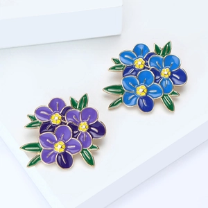 Elegante Emaille-Blumenbroschen in Blau und Lila auf weißen geometrischen Stufen