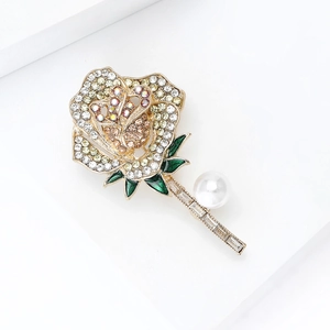 Detailopname van roosbroche met gele strasstenen, groen emaille blad en grote witte parel