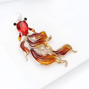 Macro detail of enamel goldfish brooch with red crystal and white pearl in golden finish