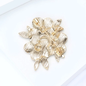 Rückansicht einer goldenen Blumenbrosche mit gebürsteter Textur und Sicherheitsnadel
