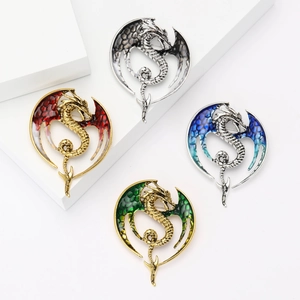 Exaggerated dragon brooches with large wings in four colors on white geometric stands