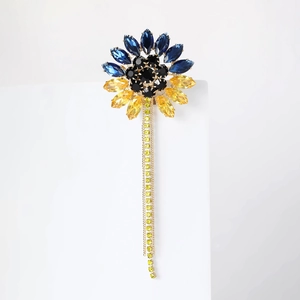 Détail d'une broche tournesol avec strass bleus et jaunes et de longues chaînes à pompons