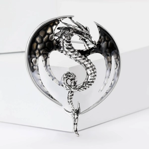 Macro detail of silver dragon brooch featuring textured black enamel wings and fantasy design