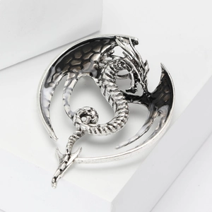 Macro detail of western dragon brooch with black and white enamel wings on silver base