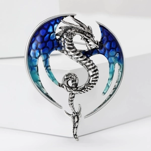 Detailed close-up of a silver dragon brooch with gradient blue enamel and honeycomb wings