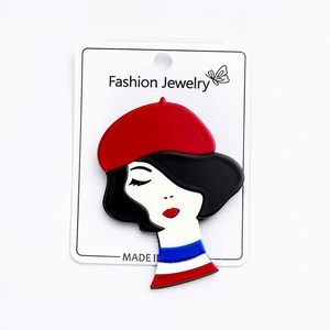 Detail of French style acrylic brooch featuring a woman with red beret and striped shirt