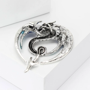 Close-up of vintage silver dragon brooch with intricate scales and secure safety pin