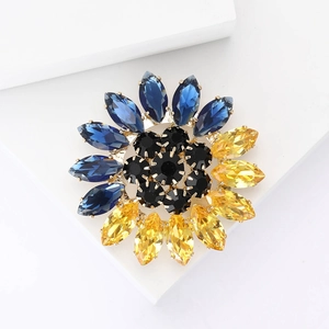 Détail macro d'une broche tournesol aux cristaux bleus et jaunes sur support géométrique