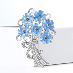Detail of blue hydrangea brooch with orange gems and rhinestone ribbon on white pedestal