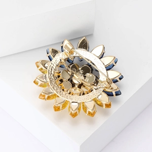 Vue arrière d'une broche tournesol avec cristaux bleus et jaunes sur socle blanc