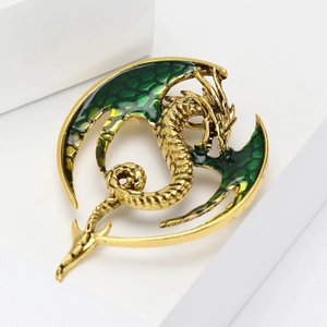 Detailed close-up of a golden dragon brooch with green enamel wings and scales
