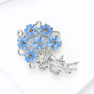 Close-up of blue hydrangea brooch with orange crystals and rhinestone bow detail