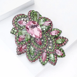 Détail d'une broche vintage avec cristaux roses et verts sur support géométrique