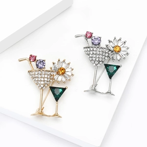 Chic cocktail glass and sunflower brooch with colorful crystals on a white platform