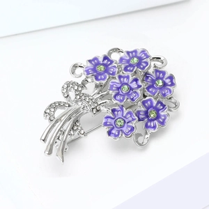 Detailed macro view of purple enamel flower brooch with green crystals and ribbon bow