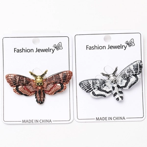 Detail of gothic moth brooches in bronze and silver finishes with skull head design