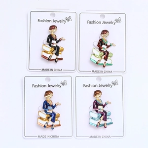 Close-up of four colorful plated enamel brooches featuring a woman sitting on books