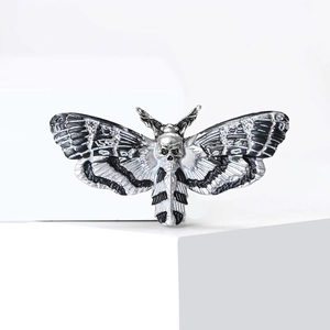 Gothic moth brooch with skull head and black striped wings on white stand